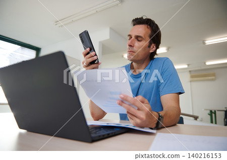 Man focused on work, analyzing charts while working on laptop in co-working office Man focused on work, analyzing charts while working on laptop in co-working office 140216153