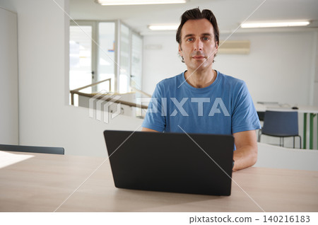 Man working on laptop in bright modern office, focused remote work and professional 140216183