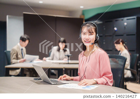 A smiling woman having an online meeting in the office. A smiling woman having an online meeting in the office. 140216427