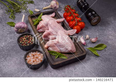 Raw chicken wings with spices and fresh vegetables on preparation table Raw chicken wings with spices and fresh vegetables on preparation table 140216471