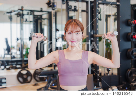 A young woman doing dumbbell training at the gym 140216543