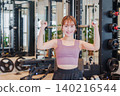 A young woman doing dumbbell training at the gym 140216544