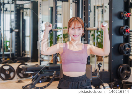 A young woman doing dumbbell training at the gym 140216544