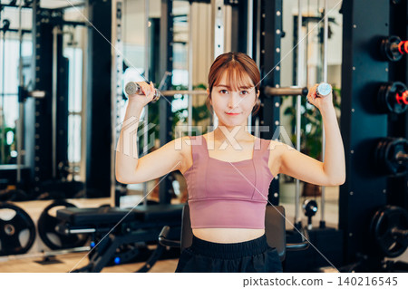 A young woman doing dumbbell training at the gym 140216545