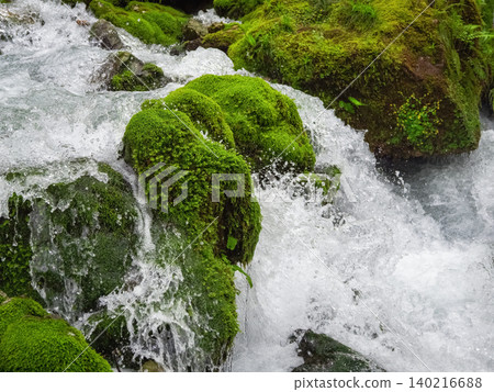 Rushing water crashes over mossy rocks Rushing water crashes over mossy rocks 140216688