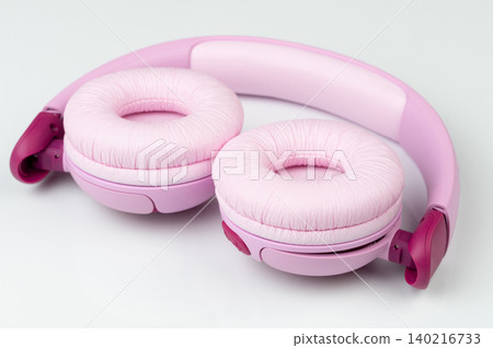 Pink headphones rest on a smooth surface in a bright setting Pink headphones rest on a smooth surface in a bright setting 140216733