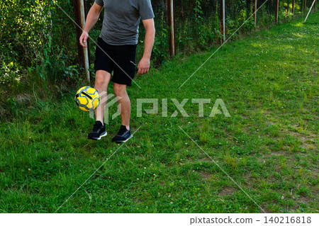 Man juggling soccer ball outdoors near a fence. Active leisure, healthy lifestyle. Man juggling soccer ball outdoors near a fence. Active leisure, healthy lifestyle. 140216818
