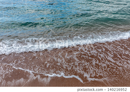Gentle sea waves washing sandy shoreline, close up coastal water texture 140216952