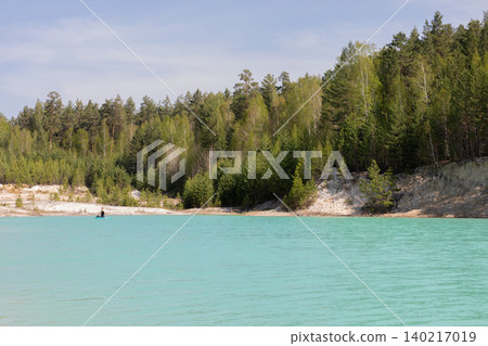 Turquoise lake and pine forest shoreline at Ural Bali quarry in summer daylight 140217019