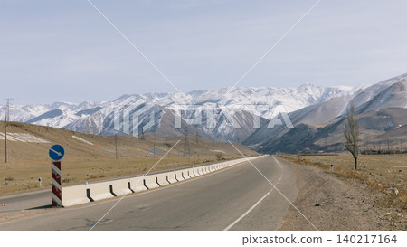 Empty highway leading to snowy Tian Shan mountains in Kyrgyzstan, Central Asia Empty highway leading to snowy Tian Shan mountains in Kyrgyzstan, Central Asia 140217164