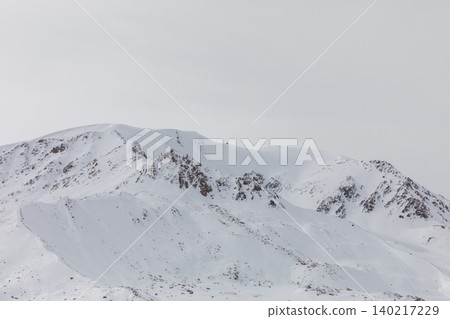 Snowy mountain ridge on Arabel Plateau with rocky peaks under overcast sky Snowy mountain ridge on Arabel Plateau with rocky peaks under overcast sky 140217229