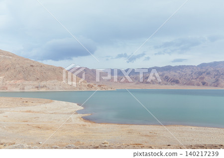 Scenic shoreline of Orto-Tokoy Reservoir with mountains and cloudy sky Scenic shoreline of Orto-Tokoy Reservoir with mountains and cloudy sky 140217239