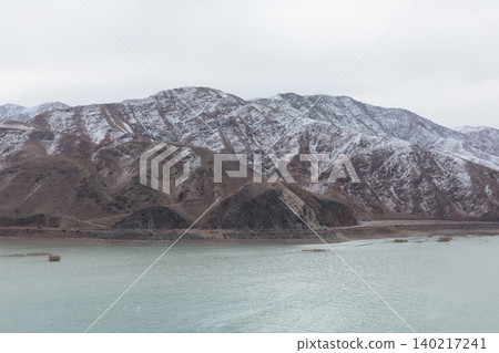 Winter mountain shoreline at Orto Tokoy Reservoir with cloudy sky, Kyrgyzstan 140217241