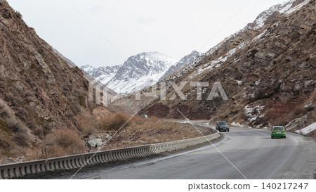 Mountain highway through a rocky valley with snow peaks in Kyrgyzstan Mountain highway through a rocky valley with snow peaks in Kyrgyzstan 140217247