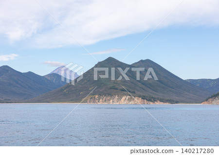 Coastal mountains and calm bay landscape in Kamchatka with volcano on horizon Coastal mountains and calm bay landscape in Kamchatka with volcano on horizon 140217280
