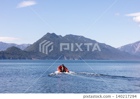 Inflatable boat heading across Avacha Bay toward mountains in Kamchatka Inflatable boat heading across Avacha Bay toward mountains in Kamchatka 140217294
