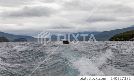 Speedboat on Kuril Lake leaving a wake under dramatic clouds, Kamchatka 140217381