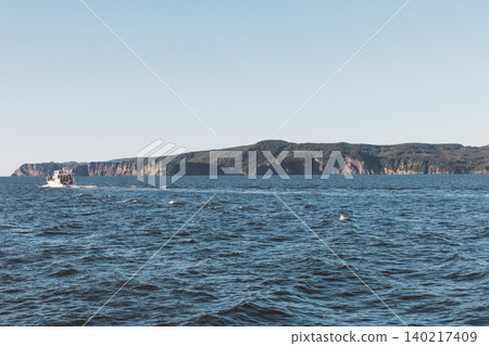 Scenic coastal cliffs and tour boat on the Pacific Ocean near Kamchatka peninsula Scenic coastal cliffs and tour boat on the Pacific Ocean near Kamchatka peninsula 140217409