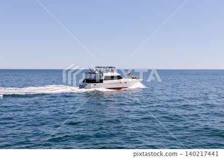 Motor yacht cruising on the Pacific Ocean near Kamchatka with wake on sunny day Motor yacht cruising on the Pacific Ocean near Kamchatka with wake on sunny day 140217441