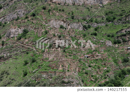 Ruins of the old mountain village of Kahib on a rocky green slope in Dagestan 140217555