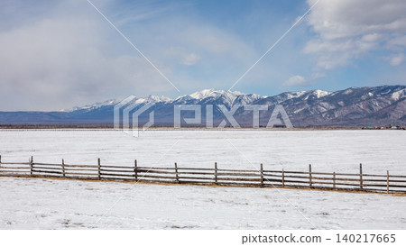 Snowy steppe plain and wooden fence with mountains in Buryatia, Russia Snowy steppe plain and wooden fence with mountains in Buryatia, Russia 140217665
