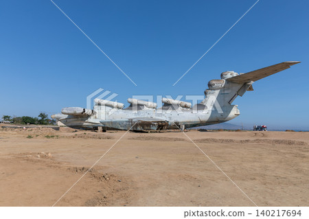 Abandoned ekranoplan ground effect aircraft on sandy shore under clear blue sky Abandoned ekranoplan ground effect aircraft on sandy shore under clear blue sky 140217694