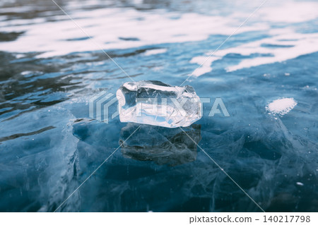 Clear ice block on frozen Lake Baikal surface with blue cracks and snow Clear ice block on frozen Lake Baikal surface with blue cracks and snow 140217798