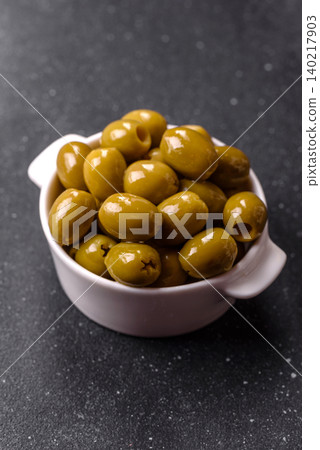 Whole green olives without pits in a bowl as an ingredient for cooking at home. Green olives 140217903