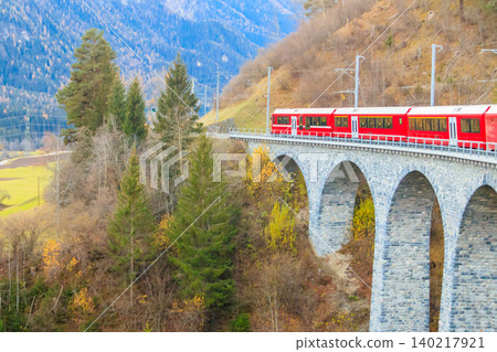 Red passenger train on Rhaetian railway in Canton Graubunden, Switzerland at autumn Red passenger train on Rhaetian railway in Canton Graubunden, Switzerland at autumn 140217921