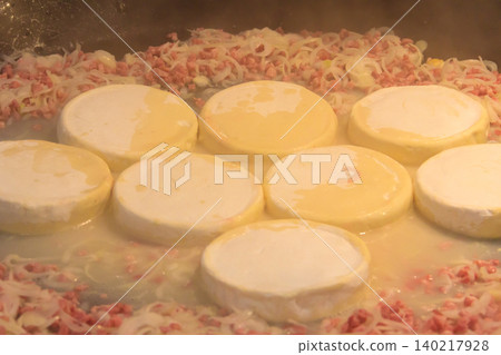 Cooking of tartiflette, a traditional French dish of scalloped potatoes, bacon and cheese, in big cauldron Cooking of tartiflette, a traditional French dish of scalloped potatoes, bacon and cheese, in big cauldron 140217928