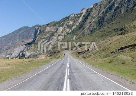 Empty highway through Altai Mountains valley with rocky cliffs and blue sky Empty highway through Altai Mountains valley with rocky cliffs and blue sky 140218028