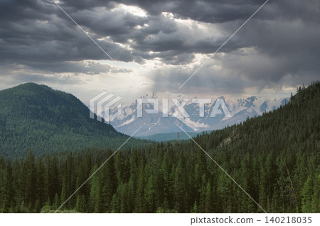 Dramatic storm clouds over Altai Mountains with sun rays and snowy peaks Dramatic storm clouds over Altai Mountains with sun rays and snowy peaks 140218035