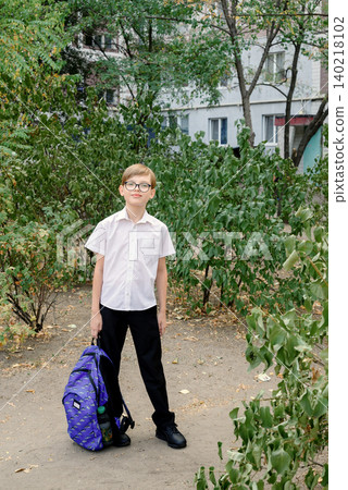 schoolboy with glasses stands outside with a backpack before the start of the school year schoolboy with glasses stands outside with a backpack before the start of the school year 140218102