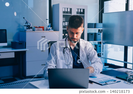 Man, doctor and laptop typing in healthcare research, communication or social media at office desk. Male medical expert working on computer in online search, browsing or chatting on tablet at clinic 140218173