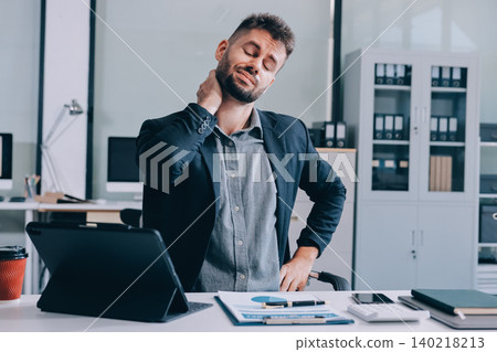 Tired worker. A tired businessman works in the evening. A man in office clothes is holding his temples. Problems in business. The businessman is trying to solve the problems that have arisen. Tired worker. A tired businessman works in the evening. A man in office clothes is holding his temples. Problems in business. The businessman is trying to solve the problems that have arisen. 140218213