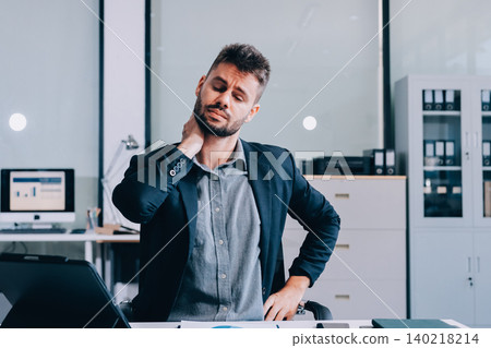 Tired worker. A tired businessman works in the evening. A man in office clothes is holding his temples. Problems in business. The businessman is trying to solve the problems that have arisen. 140218214
