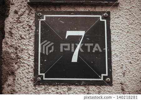 Vintage House Number 7 Sign on Weathered Textured Wall, Classic Address Plaque with Aged Surface 140218281
