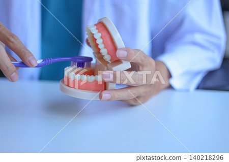 Dentist shows patient how to brush teeth correctly. Dentist shows patient how to brush teeth correctly. 140218296