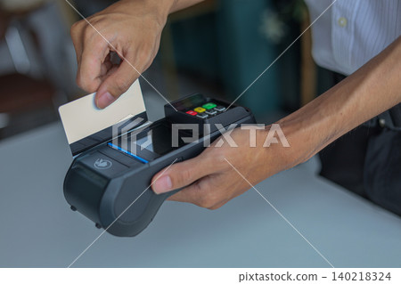 A person using a Point of Sale (POS) terminal to process a payment with a credit or debit card. A person using a Point of Sale (POS) terminal to process a payment with a credit or debit card. 140218324