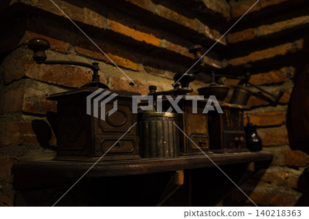Vintage Manual Coffee Grinders on Wooden Shelf Against Rustic Brick Wall 140218363