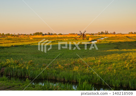 Scenic dutch polder landscape with water canal at sunset, green agricultural fields and meadows with small traditional windmill in zaanse schans netherlands countryside Scenic dutch polder landscape with water canal at sunset, green agricultural fields and meadows with small traditional windmill in zaanse schans netherlands countryside 140218509