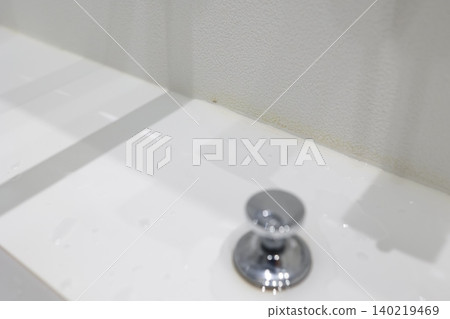 浴室的角落。牆紙上泛黃的污漬和白色的洗手台。 140219469
