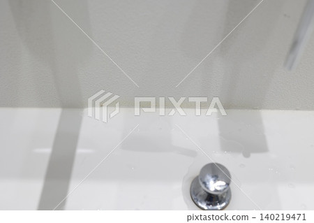 浴室的角落。牆紙上泛黃的污漬和白色的洗手台。 140219471