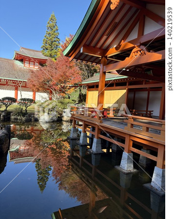 The vermilion-lacquered Noh stage and autumn leaves are vividly reflected in the Gokanosho Heike no Sato (Heike Village). 140219539