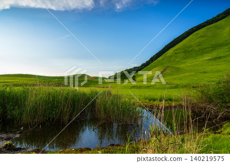Early summer on the Soni Plateau: The blue sky stretches beyond the two peaks, and the blue sky is reflected in the remaining water; the plateau is covered in fresh greenery. Early summer on the Soni Plateau: The blue sky stretches beyond the two peaks, and the blue sky is reflected in the remaining water; the plateau is covered in fresh greenery. 140219575