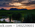 Early summer on the Soni Plateau; the setting sun peeks out from between golden clouds and sinks behind the Soni mountain range; the sun hides behind the ridgeline. 140220601