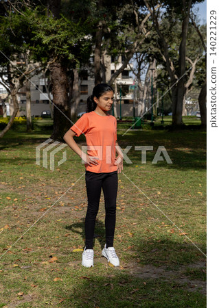 A girl in an orange shirt stands in a park A girl in an orange shirt stands in a park 140221229