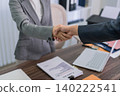 business professionals handshake agreement partnership meeting office desk with contract documents laptop modern corporate workspace collaboration success 140222541