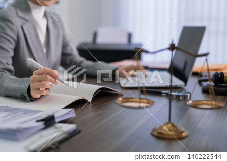 professional lawyer writing legal document notes at office desk with justice scales gavel and laptop computer working on case research consultation in modern professional lawyer writing legal document notes at office desk with justice scales gavel and laptop computer working on case research consultation in modern 140222544