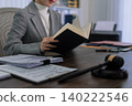 professional Asian lawyer reading legal document book studying law case research at office desk with gavel paperwork preparing trial courtroom legal 140222546